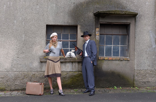 Two models get dressed up in 1930's style  vintage fashion clothes and act the role of  the gangster duo Bonnie and Clyde.
