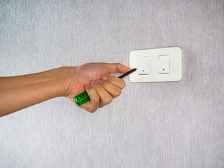 Screwdriver hand holding toward light switcher
