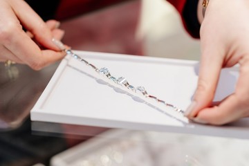 Female seller presents a silver bracelet.