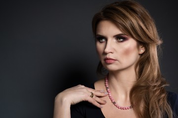 Studio beauty shot of woman with pink pearl necklace.