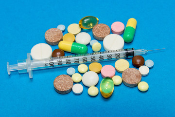 Opioid epidemic .Opioid Pills. Drug abuse Concept - different colored pills and syringe on a blue background.