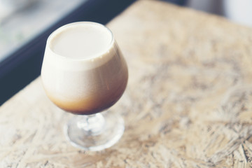 frothy sparkling nitro cold brew ready to be served at coffee shop bar environment background. coffee machine wooden table vintage