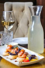 Baked shrimps in bacon on bruschettes with a glass of white wine and morsel - restaurant serve