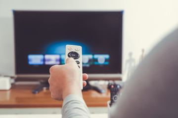 a women hand hold the remote control of the TV box in the living room