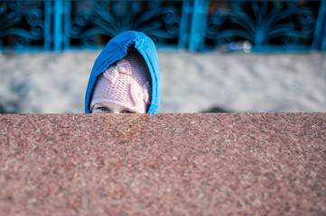 The child looks out from behind the marble fence. Only the head