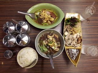 Soup, braised pork served with steamed rice. Boiled pork meatballs and topped with the sauce delicious. Another popular food in Thailand. On a wooden table