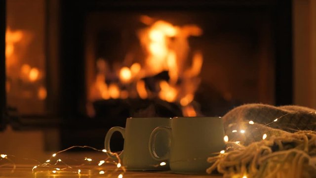 Steam from a cups with a hot cocoa on the fireplace background.   Decoration garlands of lights . 