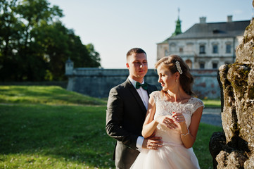 Cute newly married couple posing next to an old fountain on their wedding day.