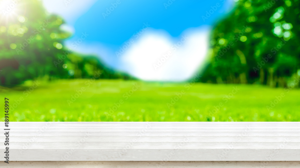 Poster empty white wood table top with blur green grass field natural park in sunny day.mock up for display