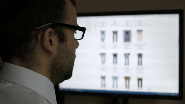 A man looks at the goods in the online clothing store, sitting at the desk. Computer online shopping. PC monitor showing blur feed page .