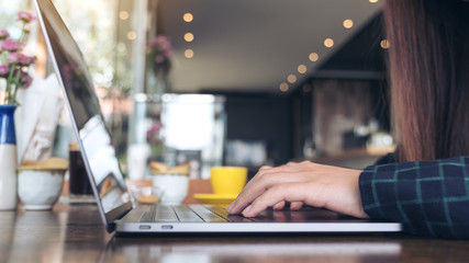Closeup image of a business woman's hands working and typing on laptop keyboard on wooden table