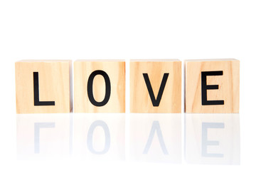 Light wood blocks with LOVE spelled out reflected on a white surface, isolated on white. Simple uncluttered design.