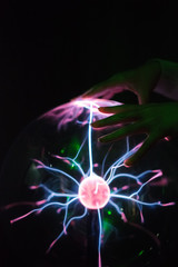 Woman's hand touching plasma globe.