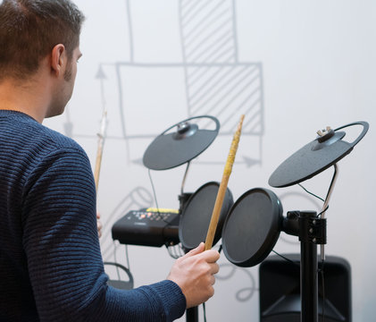 Man playing on electronic drums. Back view.