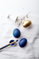 Eggs painted blue and golden colors on Easter holiday. White background, copy space, minimalistic composition