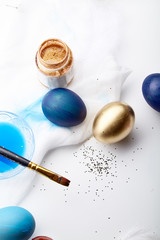 Eggs painted blue and golden colors on Easter holiday. White background, copy space, vertical composition