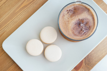 Delicious fresh traditional macaroon dessert cakes on a plate, on a wooden table with cacao and hot chocolate.
