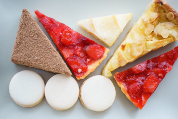 Bright sweet desserts are pastries and macaroons on a wooden table with hot chocolate and cocoa.