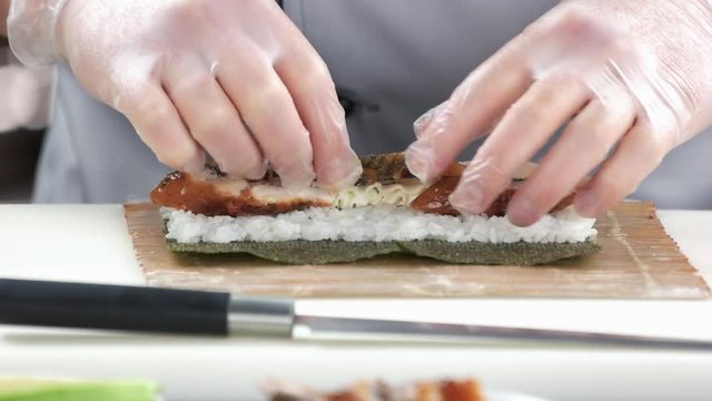 Hands making unagi sushi. Rice and smoked eel.