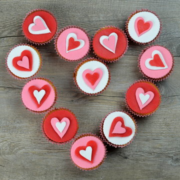 CUPCAKES decorated with hearts forming a heart shape on stone background