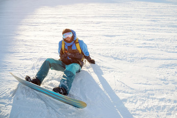 Fototapeta na wymiar Smiling man snowboarder resting sit