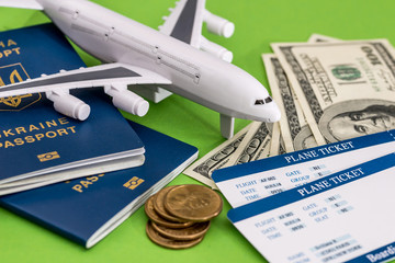 Airplane, passport, ticket and dollar on green