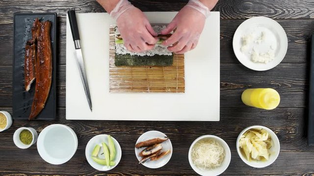 Hands making sushi, smoked eel. Unagi roll ingredients.