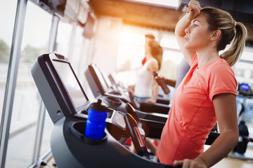 Young and beautiful lady running on a treadmill and sweating