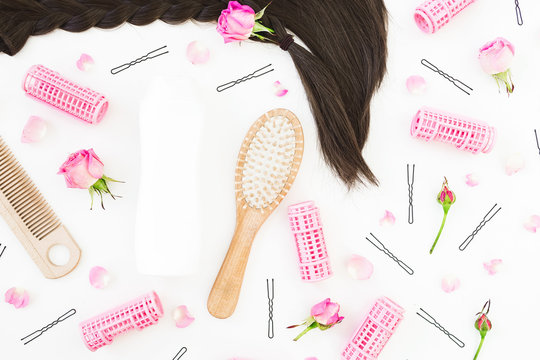 Tools for hair styling, curlers, shampoo and flowers on white background. Beauty composition. Flat lay, top view