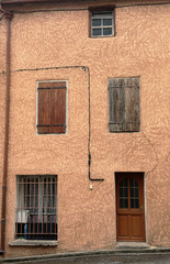 Fototapeta na wymiar Sureal cottage facade in a mottled brown and white featuring front door and shutters, remote village in the South ofFrance