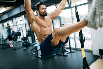 Young handsome man doing exercises in gym