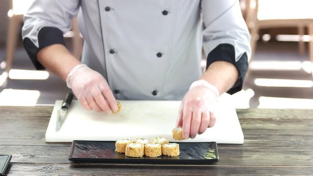 Sushi chef at cooking table. Unagi maki rolls.