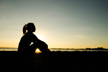 Portrait of a sad woman in a sunset with the sun in the background