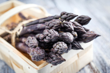 Row purple Asparagus as close-up in a basket
