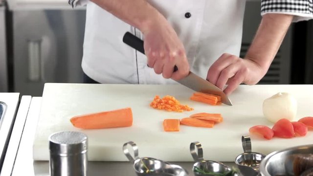 Hands of chef chopping carrot. Man preparing food, fresh vegetable.