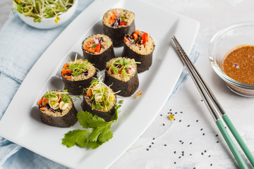 Vegan sushi rolls with quinoa, vegetables and soy-nut sauce on a white plate, light background. Vegan Healthy Food Concept.