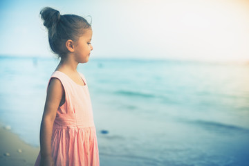 Fototapeta na wymiar Beautiful little girl at the beach. Sunblock cream for children.
