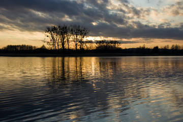 Fototapeta na wymiar Dark clouds and sunset on the lake