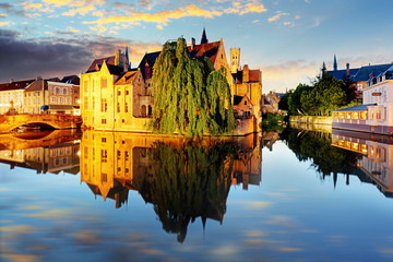Fototapeta na wymiar Canal in Bruges and famous Belfry tower on the background at sunset, night, Belgium