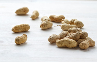 Fototapeta na wymiar Handful of peanuts in shell on a white table