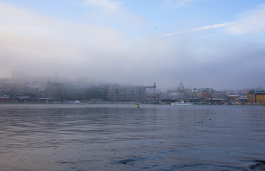 Foggy winter morning at the waterfront of Stockholm with a ferry landmarks