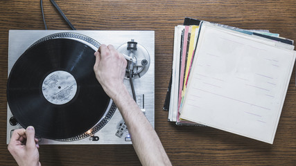 top view of the person switching the records on the playing turntable
