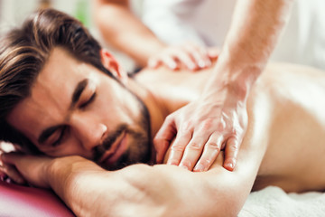 Fototapeta na wymiar Young man is enjoying massage on spa treatment. 