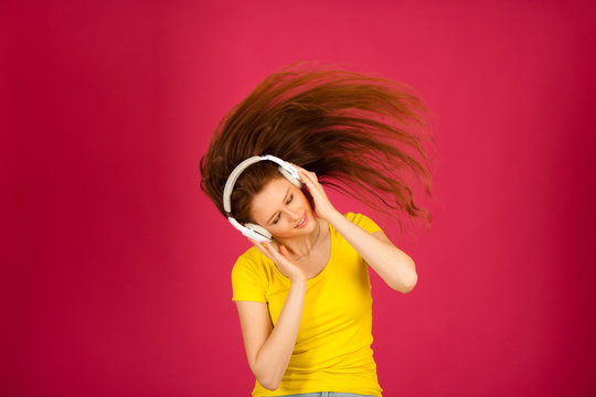 beautiful caucasian woman dance as she listen music over pink background