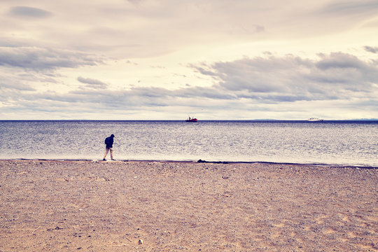 Lonely person walks along a beach, color toned conceptual picture.