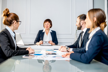 Senior businesswoman talking during the conference with young colleagues in the office