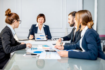Senior businesswoman showing charts during the conference with young colleagues in the office