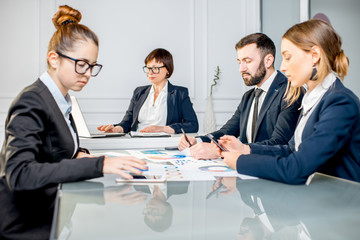 Business people working with charts and documents sitting at the table during the conference in the office