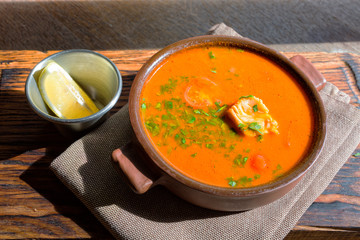 Marmitako soup in a ceramic bowl on a wooden board