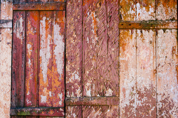 Old grunge and weathered red, yellow and white wooden wall planks texture background marked by long exposure to the elements outdoors.